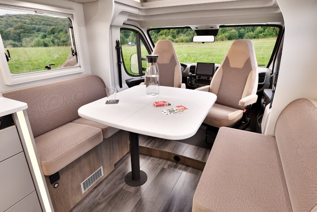 Carado motorhome interior with seating area, table and swivelling cab seats