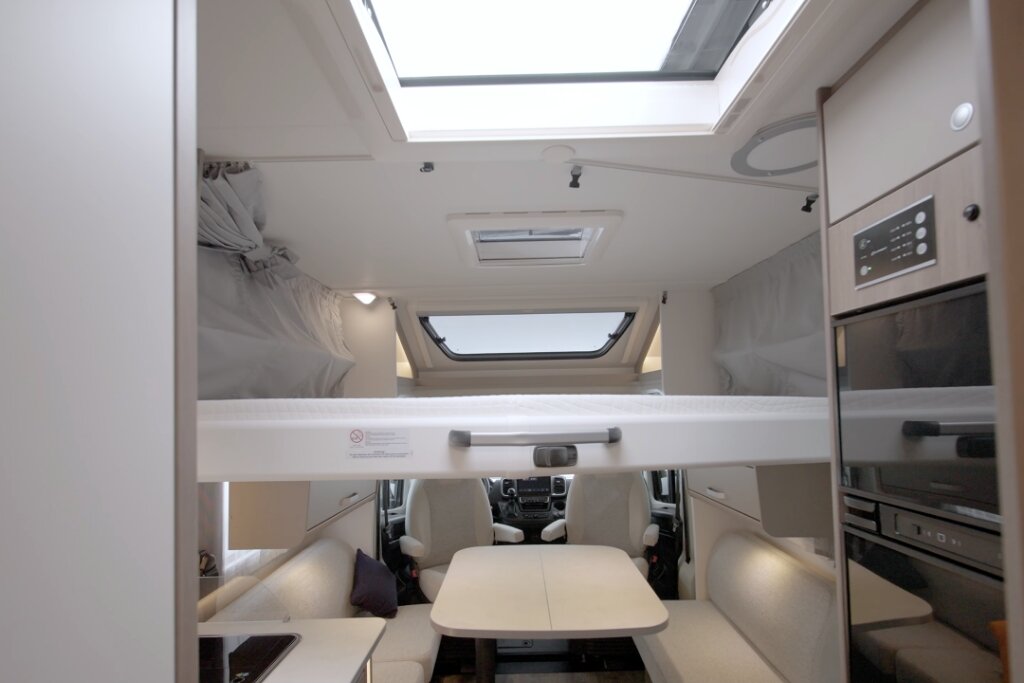 Carado motorhome interior with drop-down bed above the seating area, roof windows and a forward view