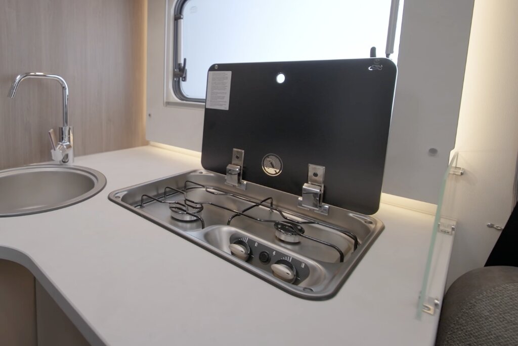 Carado motorhome kitchen unit with a round sink and two-burner gas hob under a raised glass cover