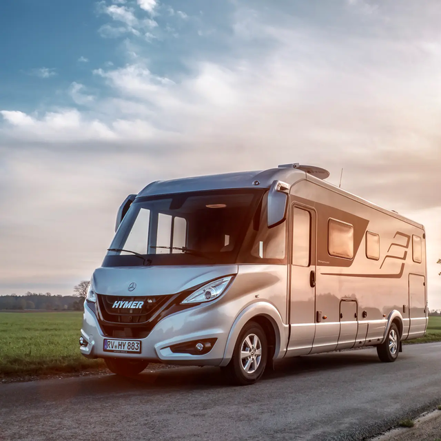 HYMER B-Class Masterline on the road in a flat landscape with green meadows and trees