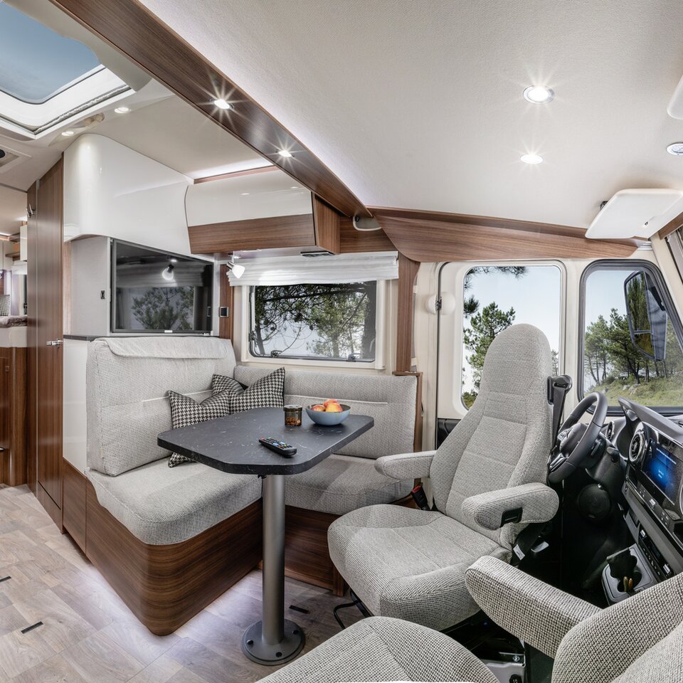 Lounge seating group with driver's seats and decorative cushions, TV plasma and kitchen in the HYMER B ModernComfort
