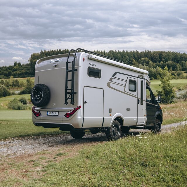 HYMER ML-T syns bakifrån när den står på en åker mellan två ängar.