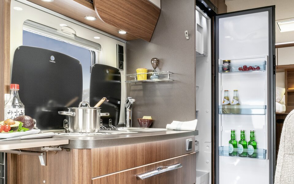 Kitchen block with worktop extension, saucepan on the stove, other kitchen accessories, open refrigerator in the HYMER ML-T