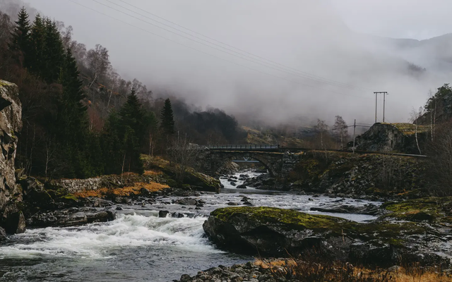 Uitzicht op een rivier, een verkeersbrug en mist op de achtergrond