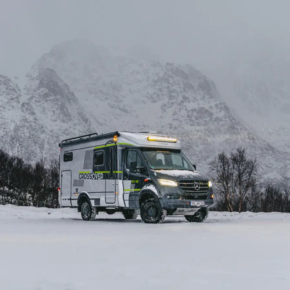 Zijaanzicht van de HYMER ML-T 570 CrossOver, hoge besneeuwde bergen op de achtergrond