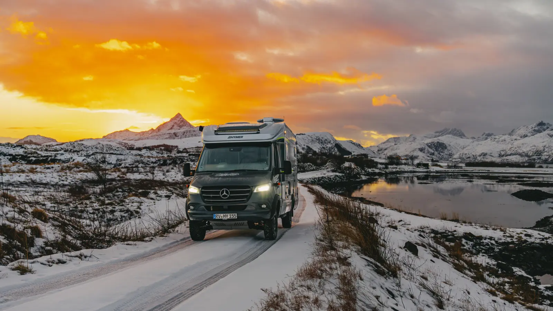 HYMER ML-T 570 rijdt op de weg, besneeuwde bergen en een prachtige zonsondergang op de achtergrond
