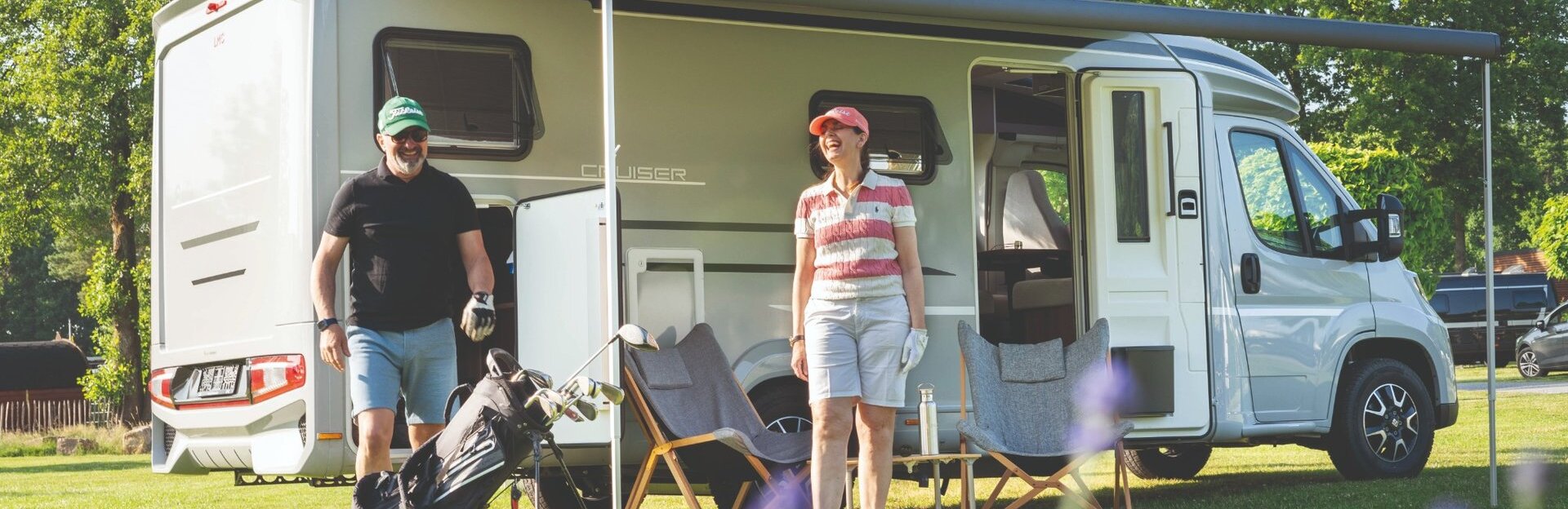 Pärchen steht mit Golf Equipment vor dem LMC Cruiser 